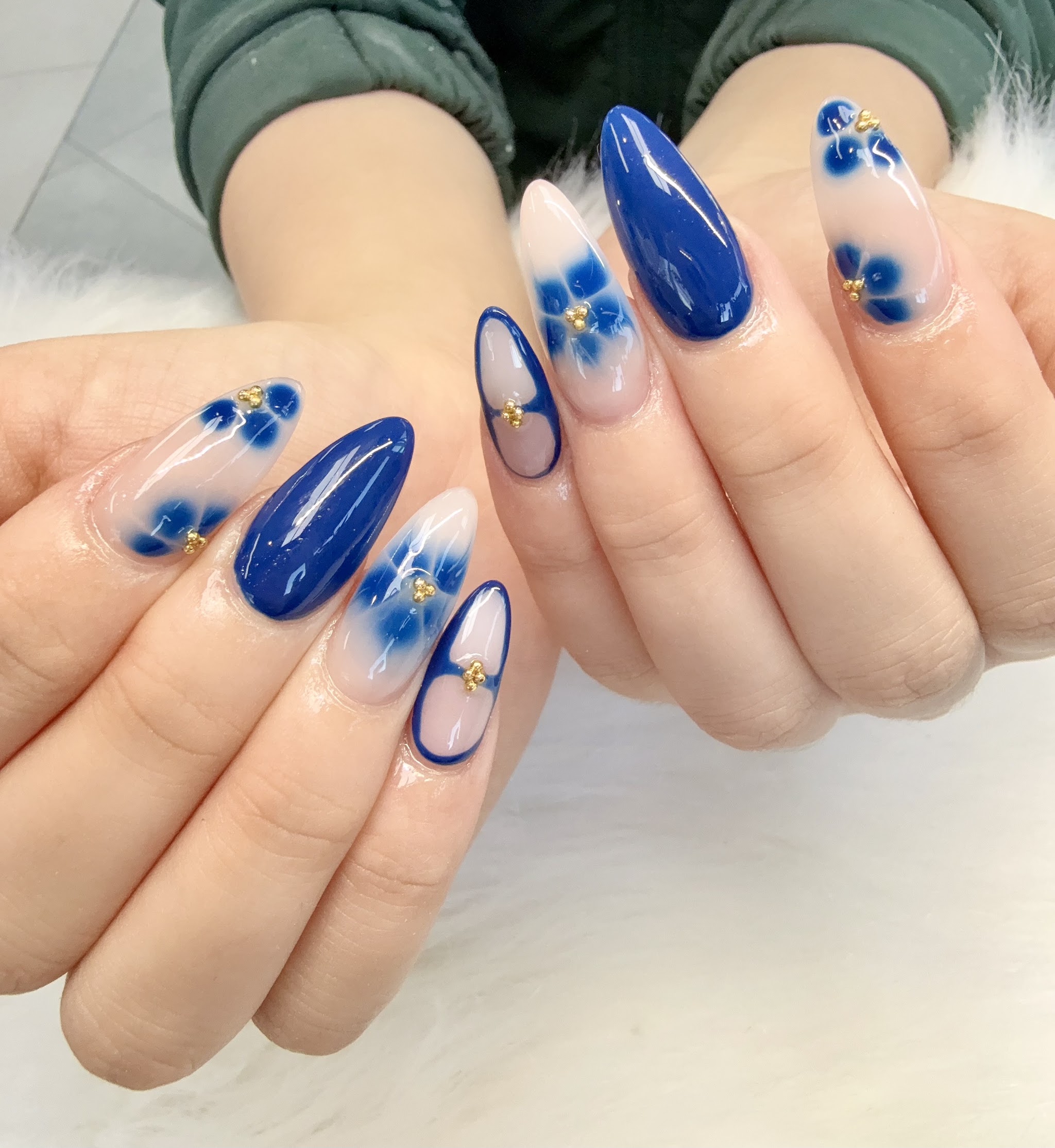 Almond nails in navy blue with hand-painted florals and gold accents