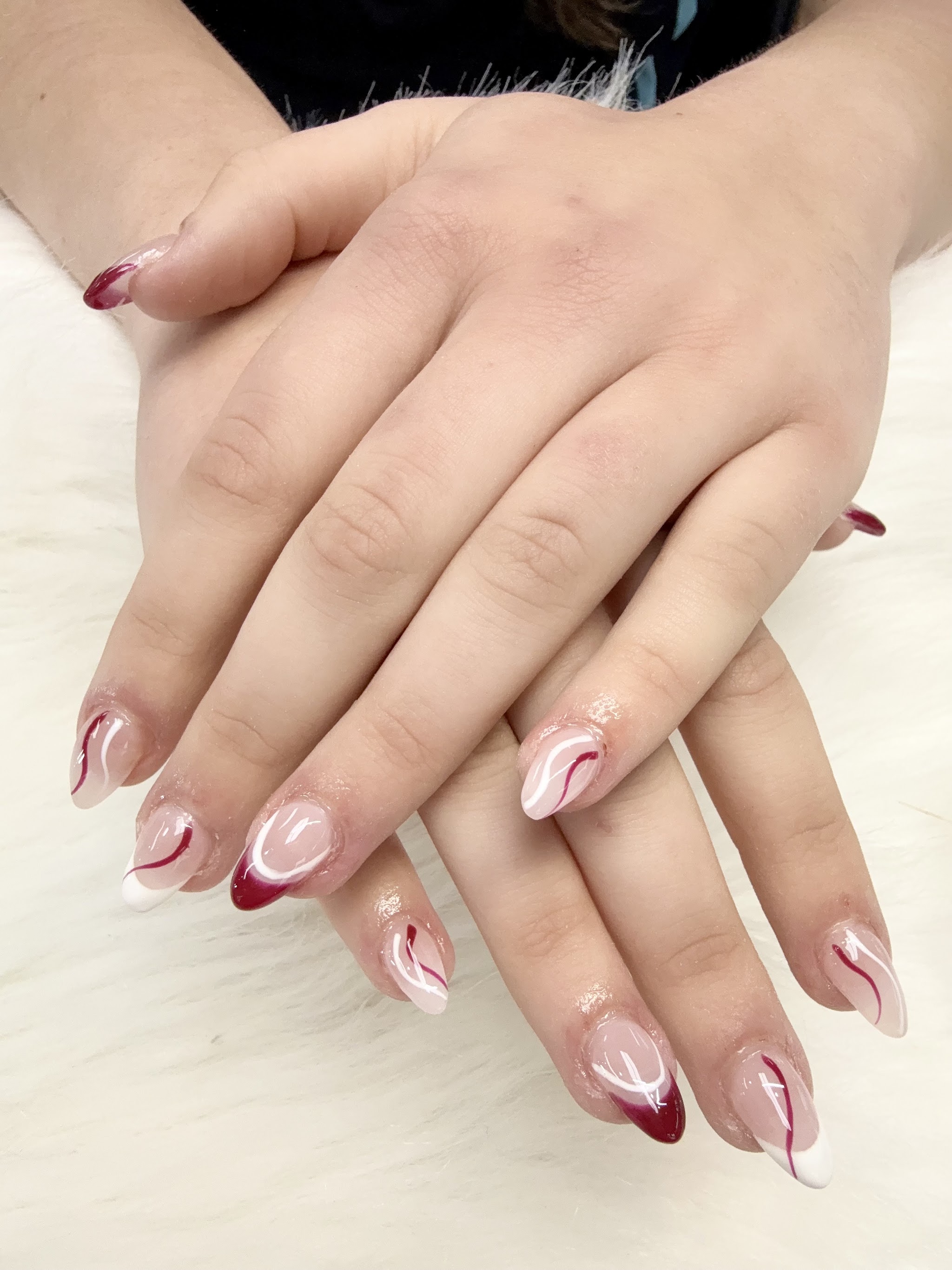 Almond nails with maroon and white swirl French tips